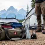 Camper preparing camping gear at a Parks Canada-style campground in Alberta with the tent, lantern, and Rocky Mountains in the background.