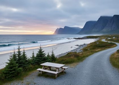 “Dawn coastal view at Gros Morne National Park with ocean waves on a remote white-sand beach and a campground path lined with evergreens toward distant cliffs.”